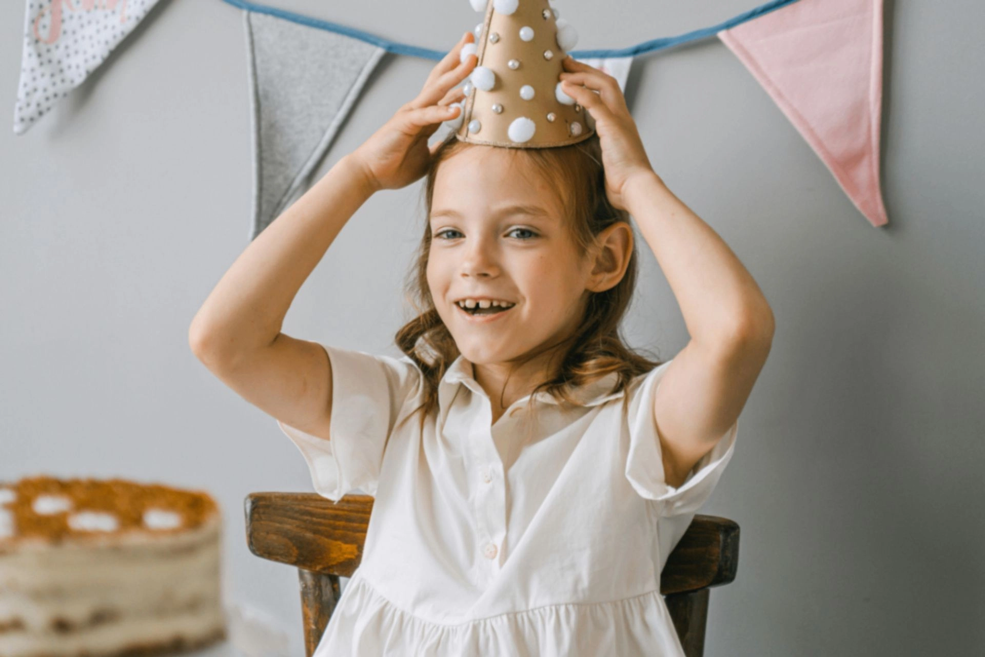 Girl in a paper party crown smiling at her birthday party